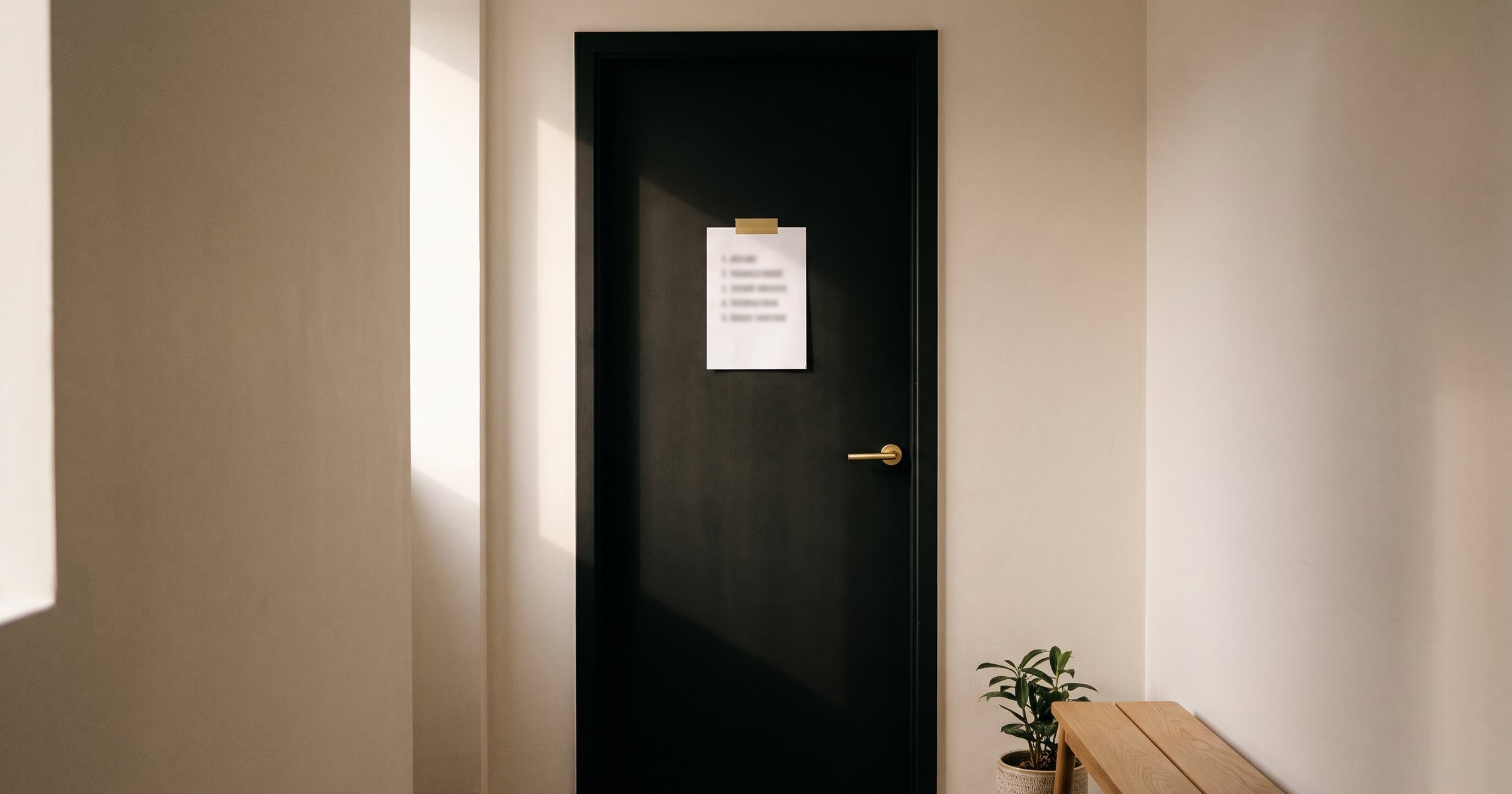 Porta preta de sala com uma folha de regras presa por fita dourada